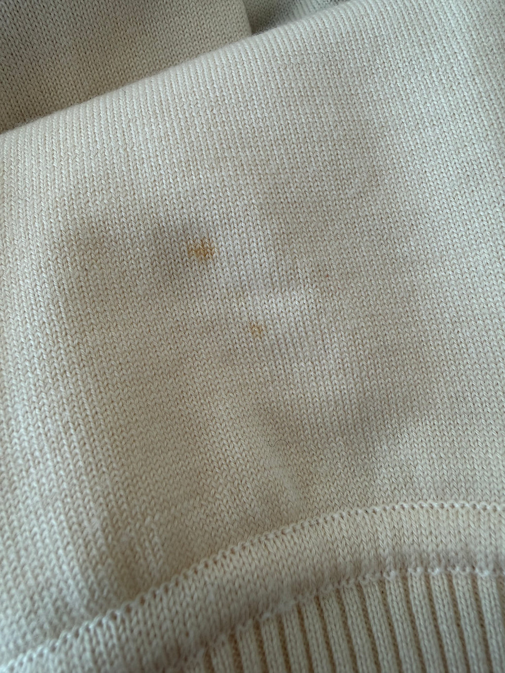 Close-up of the small marks on the cream knit, as noted in the condition report