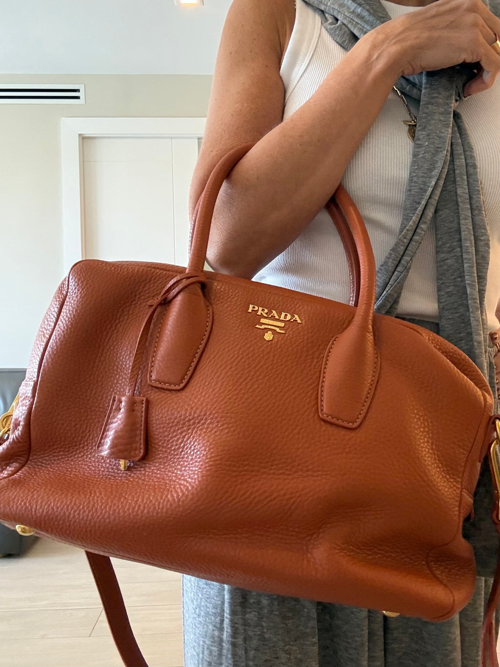Prada burnt orange pebbled leather satchel with gold hardware worn on the arm